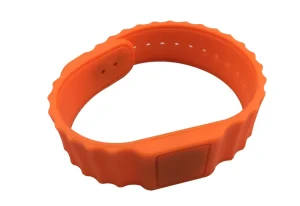 A 13.56 MHz RFID Wristband iliyotengenezwa kwa silikoni ya chungwa, iliyo na clasp, vitobo kwa ajili ya kurekebisha ukubwa, na teknolojia jumuishi ya RFID.