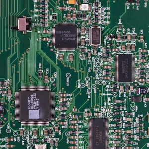 Kaw-up saib ntawm ntsuab luam ntawv Circuit Court board adorned nrog ntau yam integrated circuits, resistors, capacitors, thiab lwm yam khoom siv hluav taws xob, showcasing cov kev nce qib hauv kev sib txuas raws li cov ncauj lus kom ntxaws hauv "Kev Tshaj Tawm Tshaj Tawm hauv RFID Technology Shaping the Future of Connectivity.