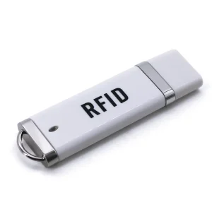 Um leitor IC RFID, apresentando um dongle USB branco elegante com detalhes prateados e "RFID" rotulagem, é elegantemente exibido contra um fundo branco imaculado, exemplificando seu design refinado.