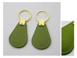 Two green Leather Proximity Key Fobs with gold metal rings and white stitching are displayed side by side on a white background. A close-up detail of the stitching is shown in an inset image.