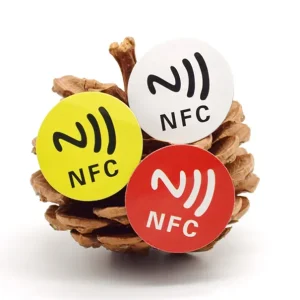 Երեք NFC պիտակներ դեղին գույնով, սպիտակ, իսկ կարմիրը փակցված են սոճու վրա.