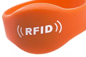 Közelkép egy narancssárga RFID karszalagról eseményekhez, az "RFID" szöveggel" jelzővezetékekkel mindkét oldalon.